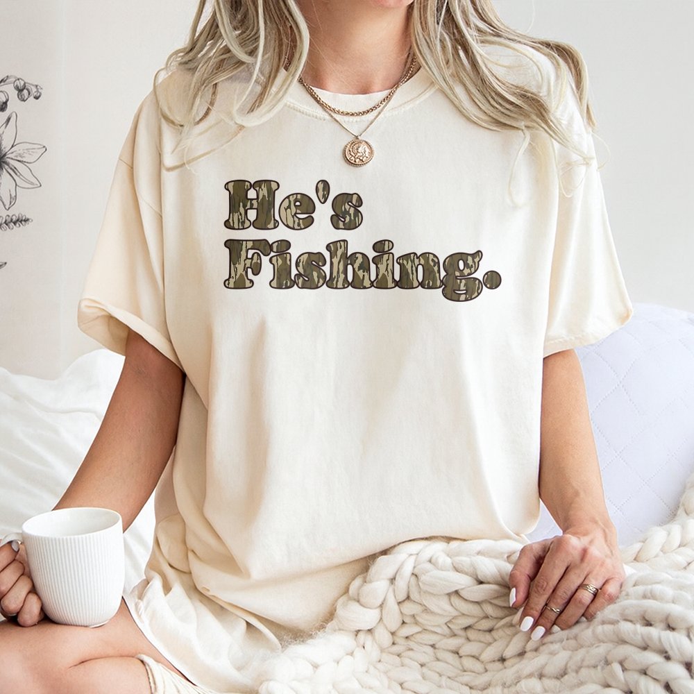 He's Fishing T-Shirt | Camo Text Graphic Design | Premium Cotton Tee | Gift for Anglers and Outdoorsmen