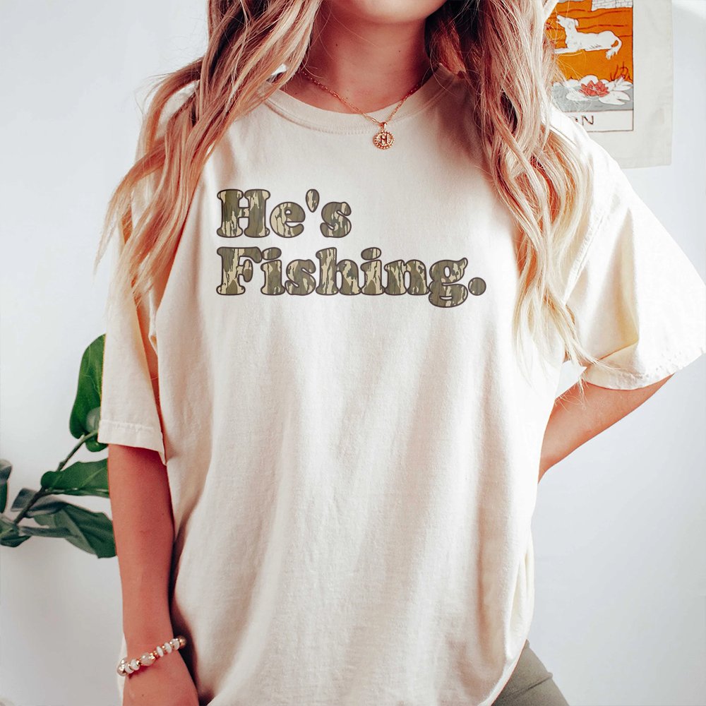He's Fishing T-Shirt | Camo Text Graphic Design | Premium Cotton Tee | Gift for Anglers and Outdoorsmen